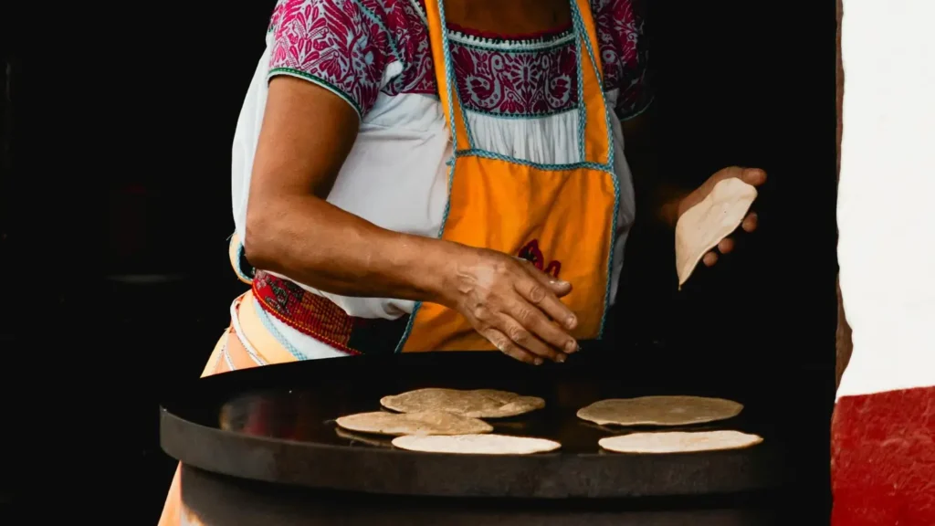 Senior woman preparing traditional flatbreads on a street in Cuetzalan, Mexico.